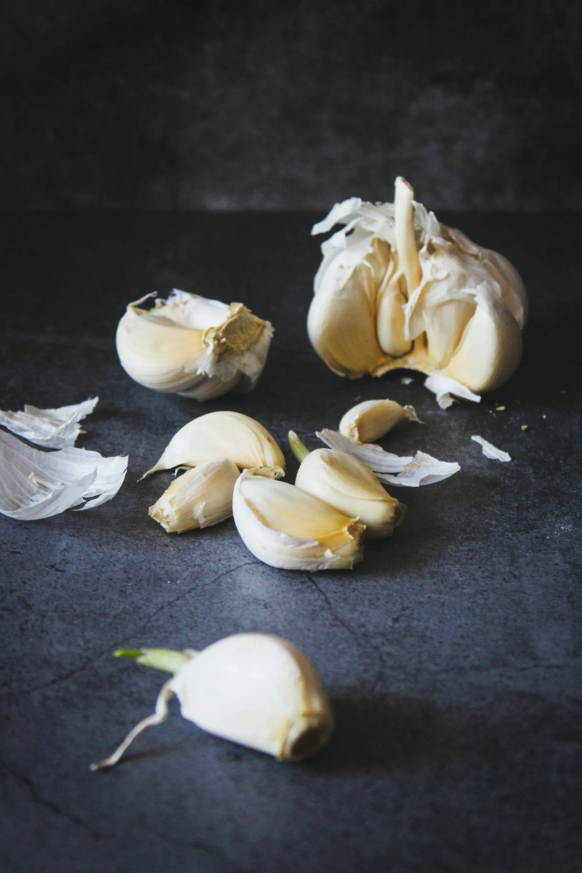 Spicchi e bulbi d’aglio su una superficie scura di ardesia
